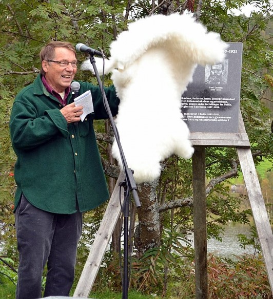 Etter litt om og menn med å få løsnet skinnfellen, kan Gunnar Stålsett avduke minneplata over Helene og Carl Lassen. Foto Ida Løchen