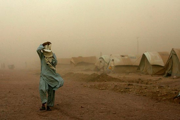 En internflyktning vandrer gjennom en støvsky i Pakistan like før monsunen i juli 2009. Pakistan har de siste årene vært åsted for en rekke ødeleggende varmebølger og kraftige monsuner. (Foto: Akhtar Soomro, Scanpix/Reuters)